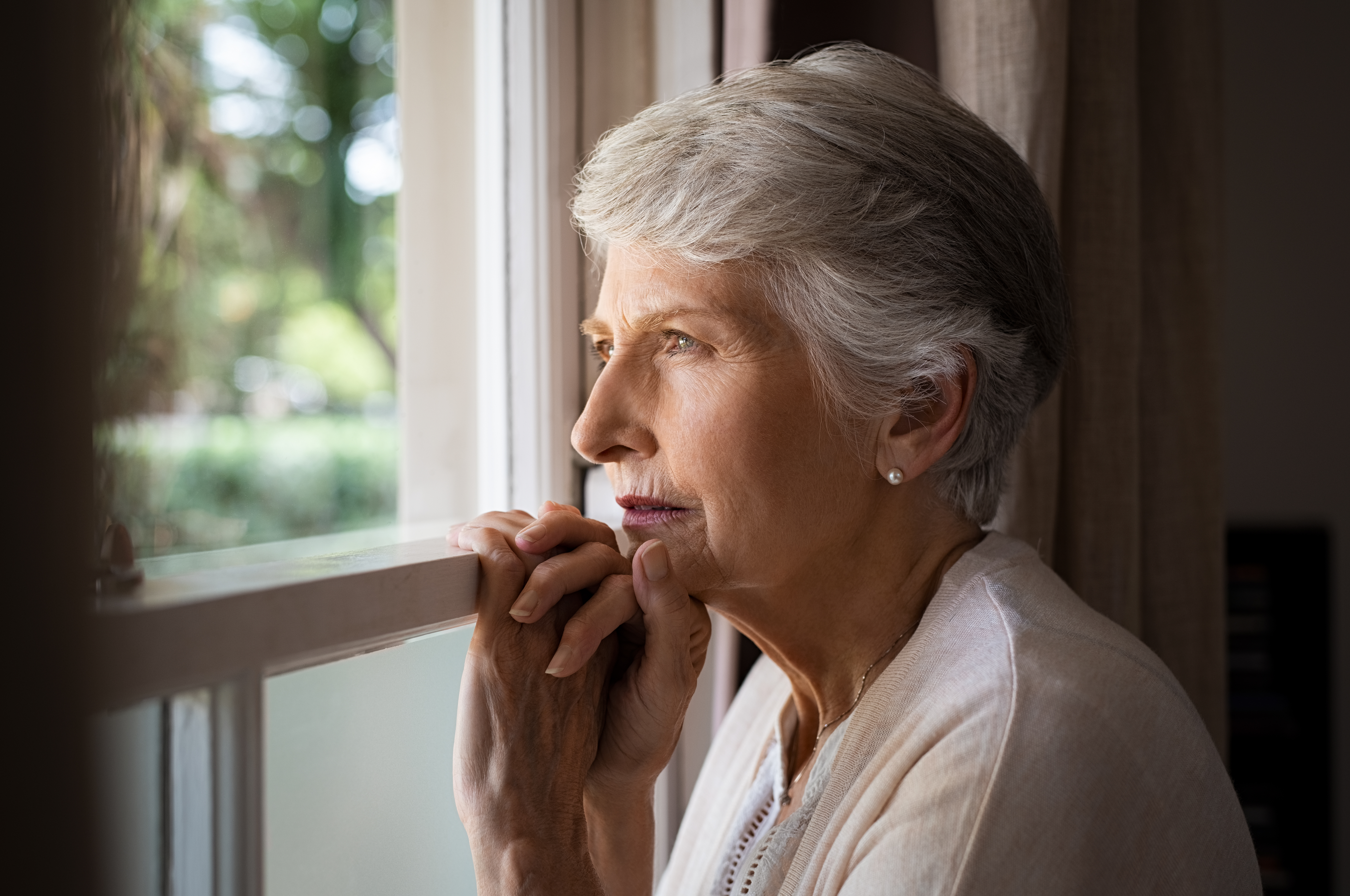 woman looking out window at incoming storm Miami